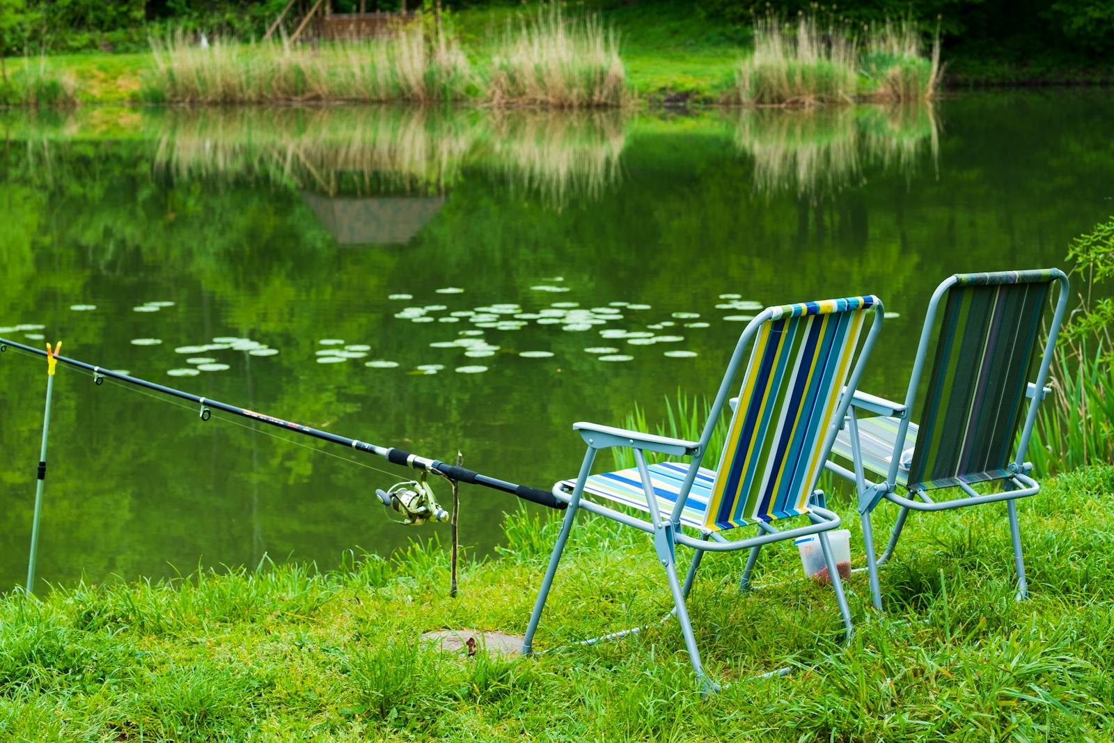 A serene fishing setup with chairs by a lakeside, perfect for outdoor relaxation.