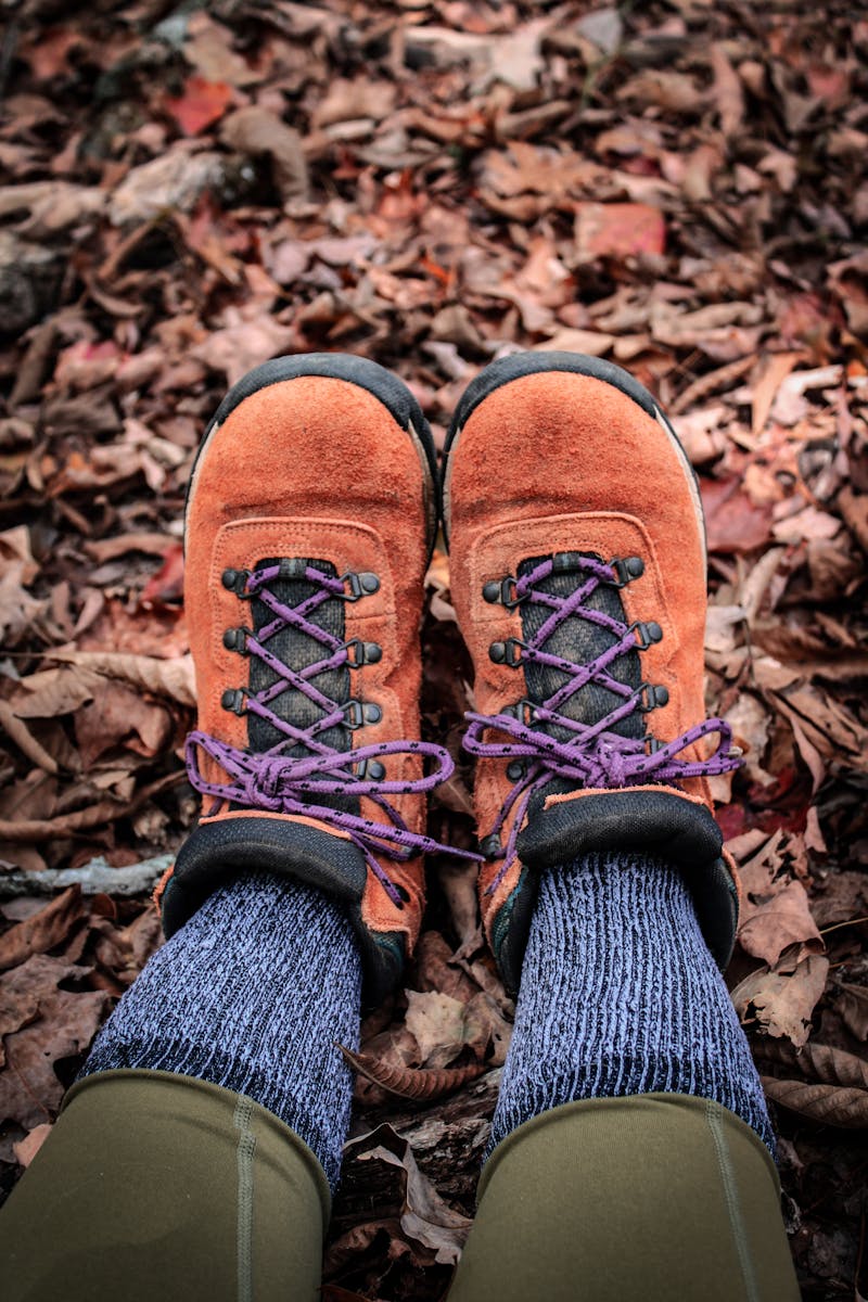 Close-up of hiking boots on fallen leaves, perfect for fall adventures.