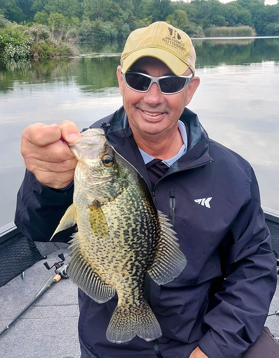 Man holding a large crappie fish on a boat