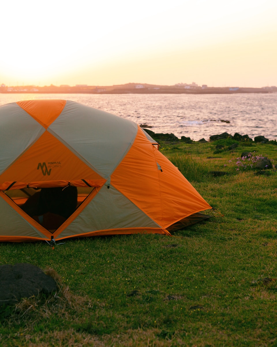 Why Early Spring Camping Beats Summer Every Time orange and gray dome tent on green grass field near body of water during daytime