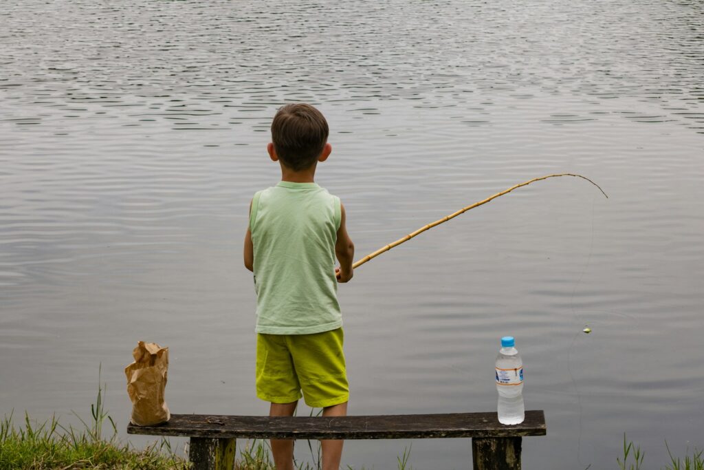 a young boy standing on a bench next to a body of water