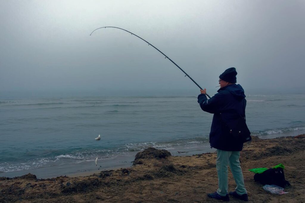 Man fishing on foggy beach in Alicante, Spain at dawn.